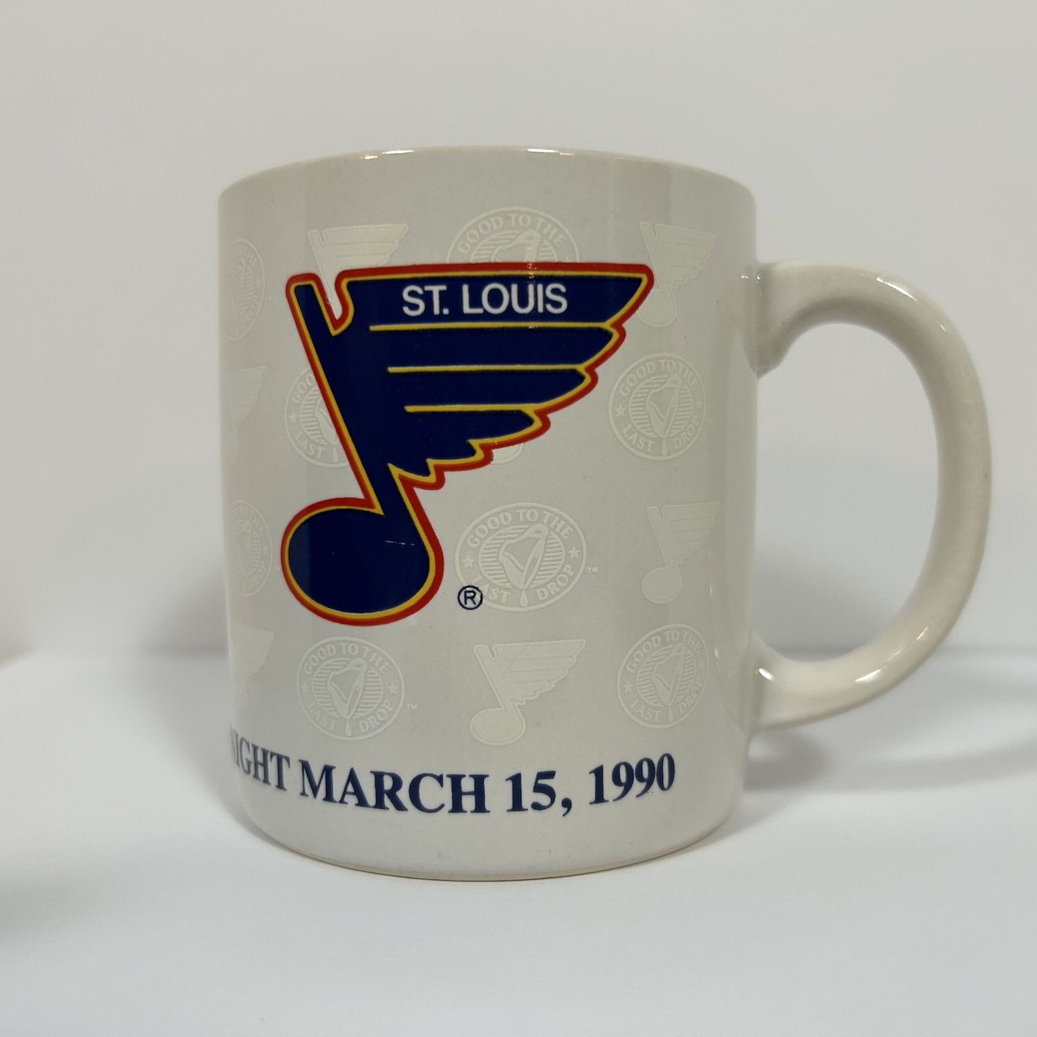 vintage white coffee mug with vintage blue, white and red St. Louis Blues Logo on top of blue background